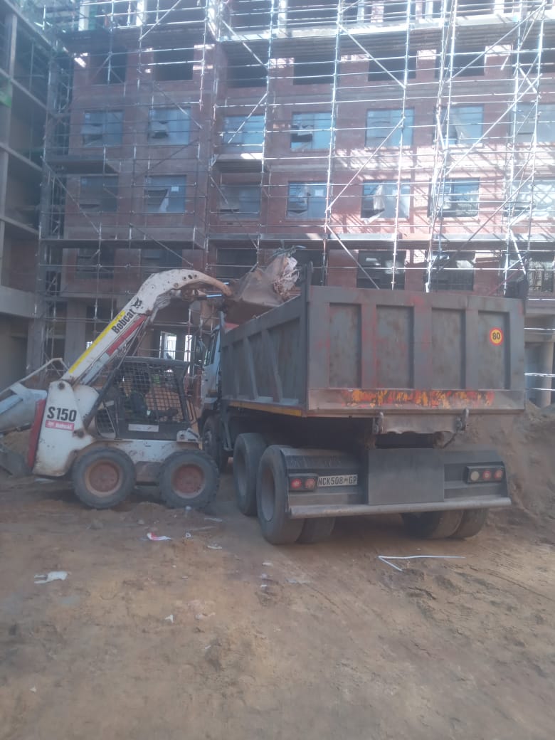 Skid-steer loader loading rubble into a dump truck